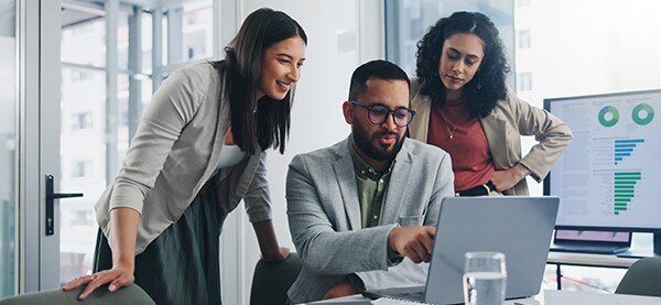 three people in an office looking at a computer screen
